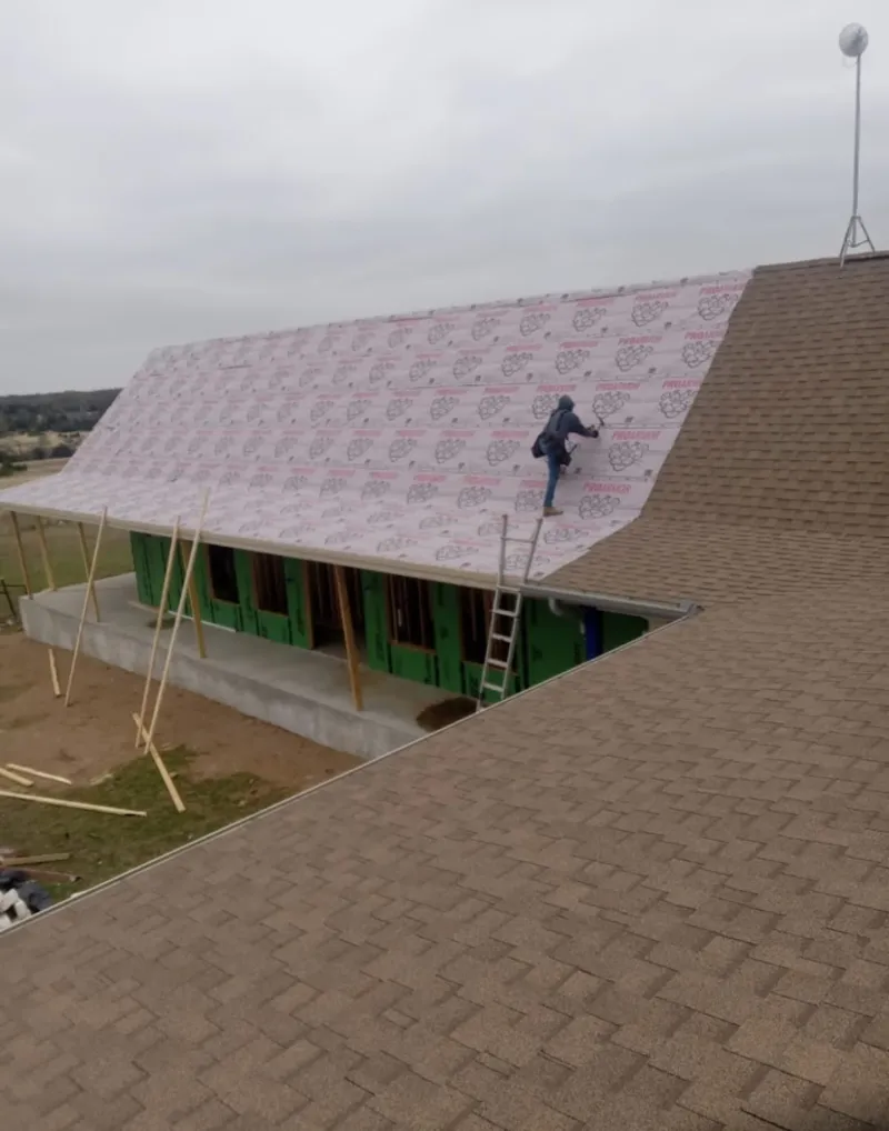 Worker preparing underlayment for a metal roof installation in Groton